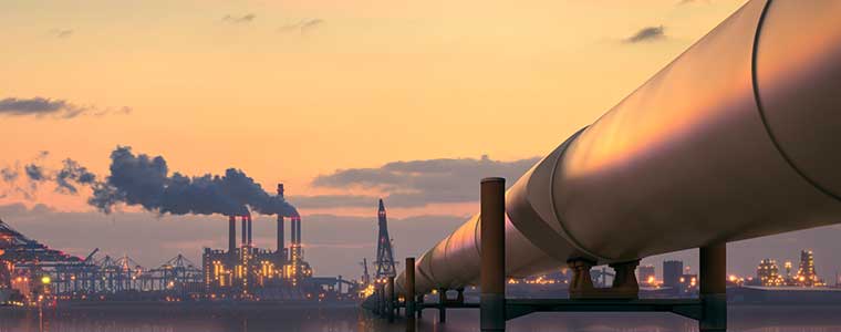 Industrial pipeline infrastructure with elevated pipe arches against a clear sky at sunrise or sunset.